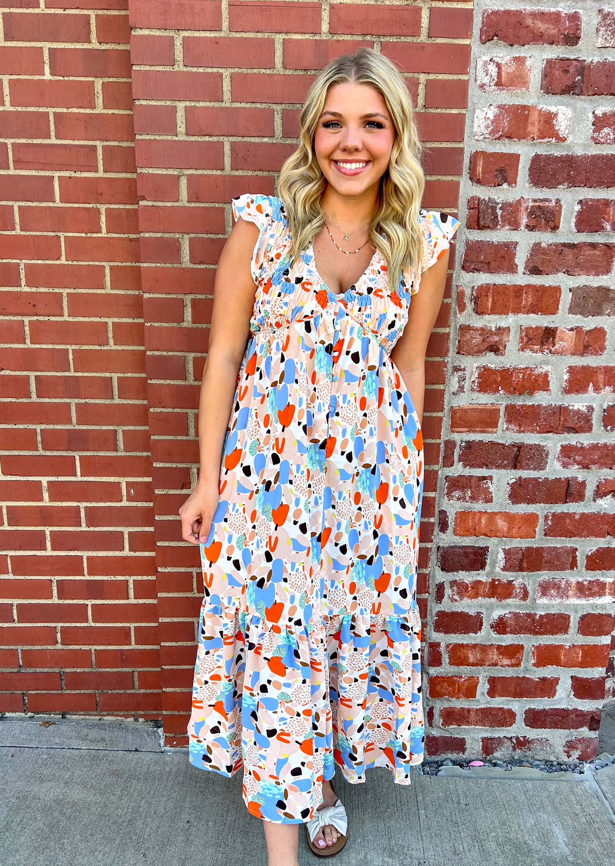 Get ready to turn heads in our fabulous Tiered Midi Dress. This versatile dress features a trendy v-neckline, chic midi length, functional button down design, and flattering front and back smocking. The tiered design adds a playful touch, making this dress perfect for any occasion.